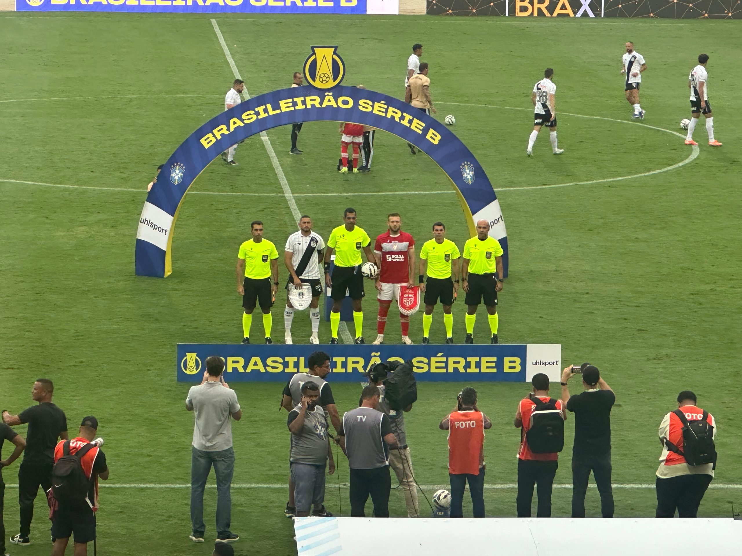 Jogadores do CRB comemorando um gol em campo, com o árbitro em segundo plano.