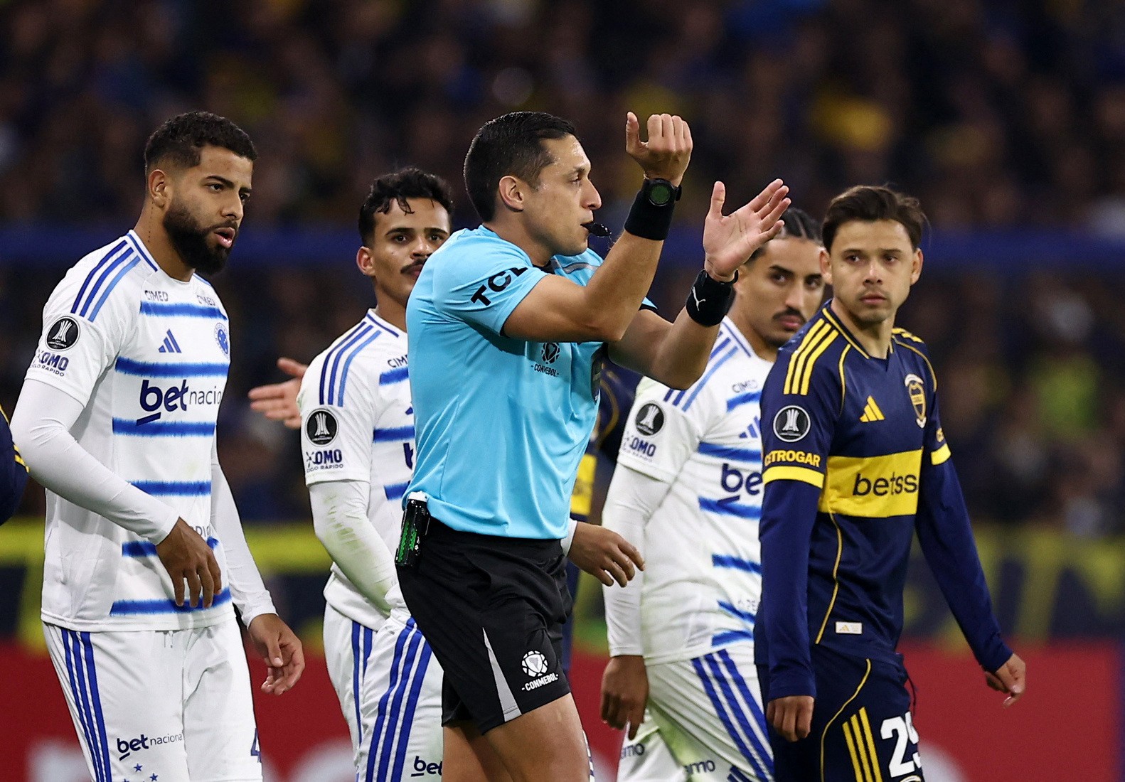 O árbitro Jesús Valenzuela em campo, analisando um lance no monitor do VAR durante a partida entre Boca Juniors e Cruzeiro pela Conmebol Libertadores.
