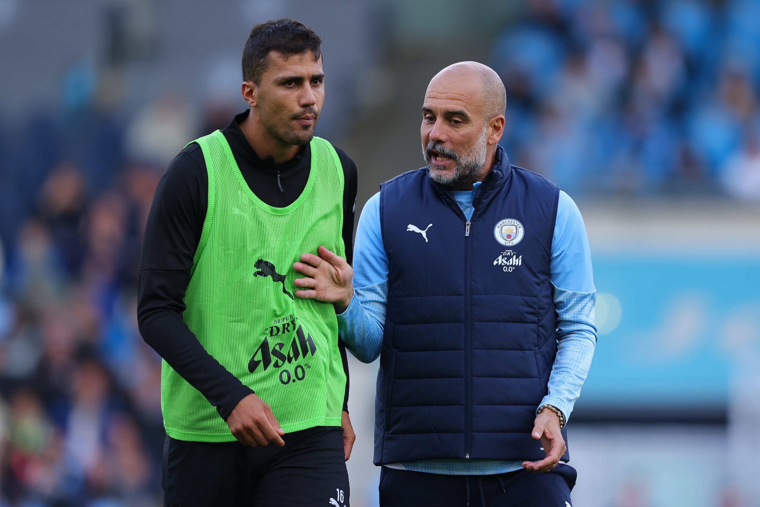 Rodri e Pep Guardiola conversam durante sessão de treinamento do Manchester City, com o jogador espanhol ouvindo atentamente o técnico.