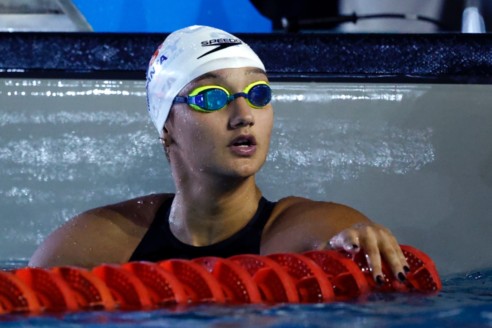Maria Fernanda Costa celebrando após vencer os 200m livre no Troféu Maria Lenk 2026, com Stephan Steverink e Murilo Sartori em ação na piscina e Davi Vallim.
