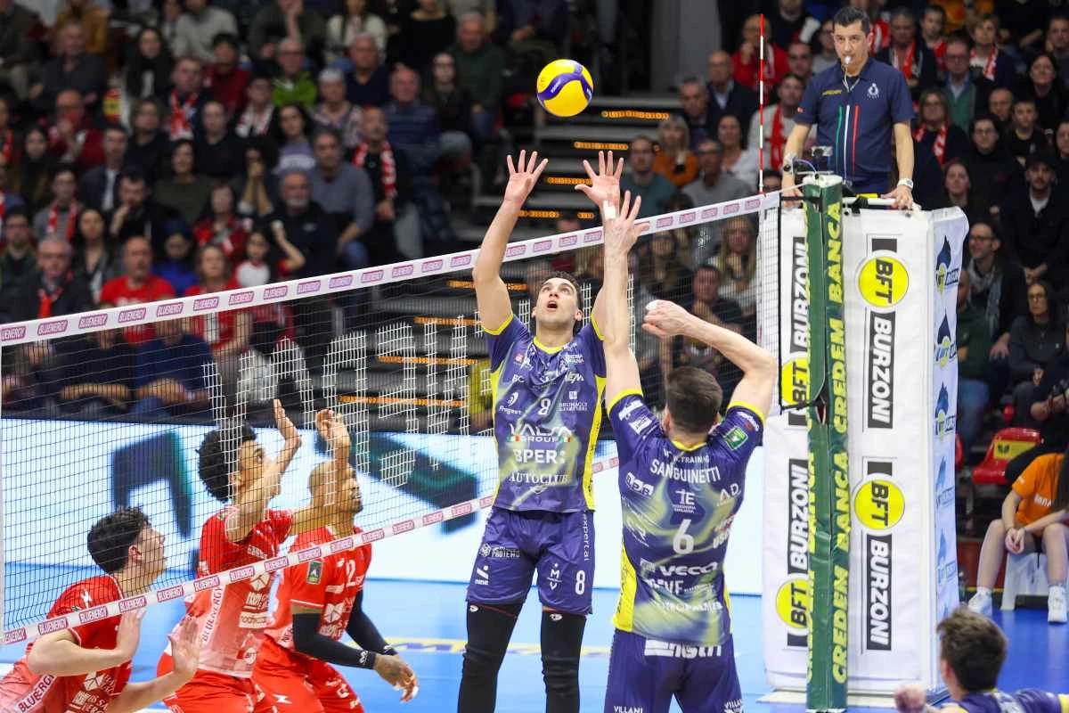 Um levantador de voleibol em quadra, com expressão de concentração, preparando-se para distribuir a bola para um ataque.
