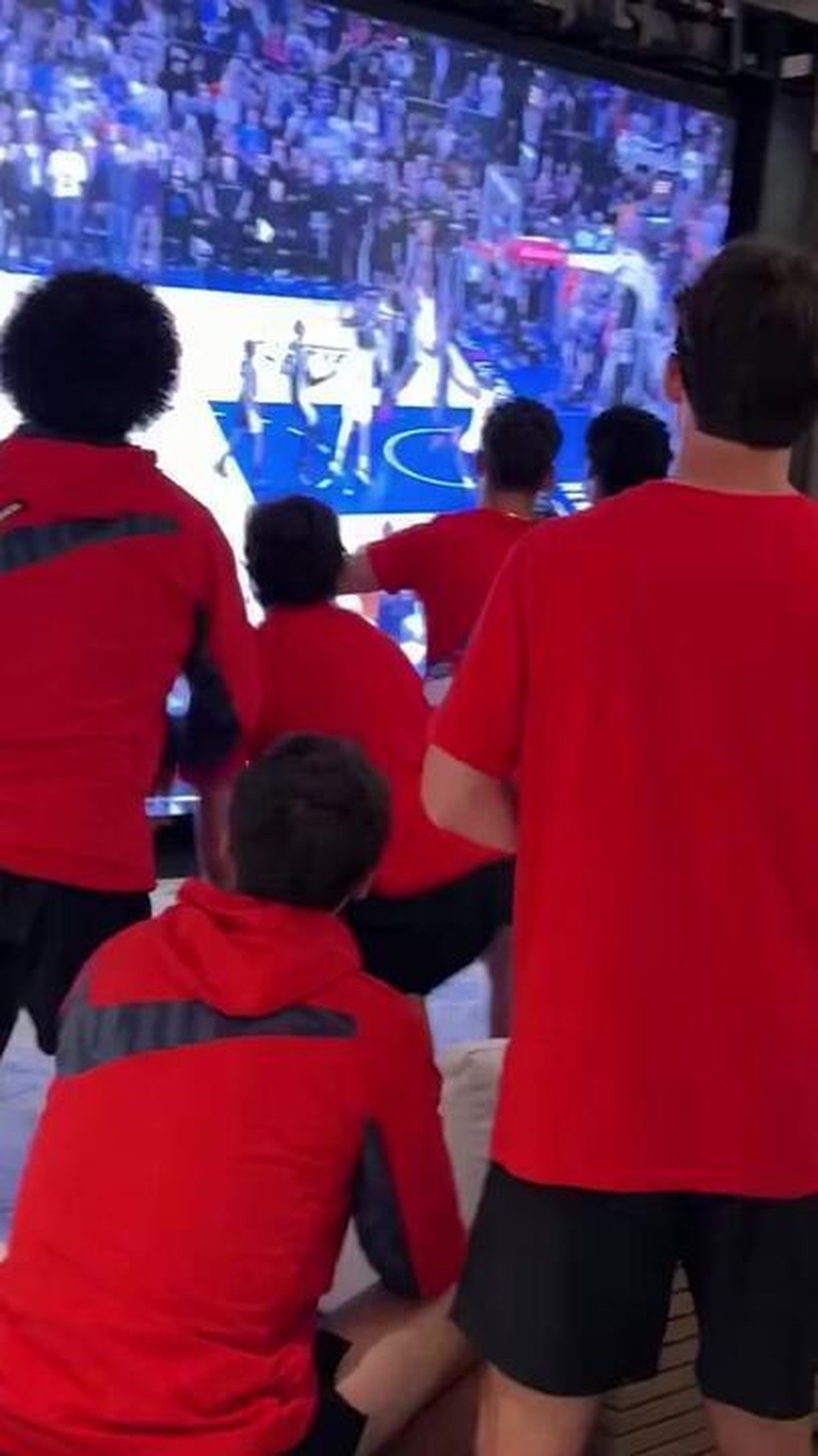 Jogadores da seleção dos EUA em concentração assistindo a uma partida de basquete na TV.
