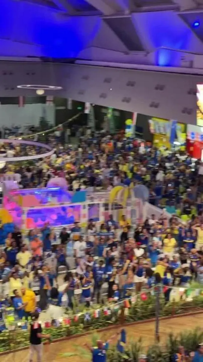 Torcedores de Curaçao celebram o histórico empate em um shopping, com telão mostrando o jogo da Copa do Mundo.