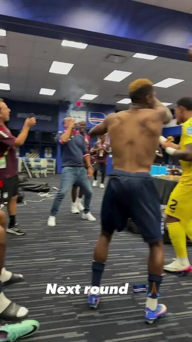 Técnico de Cabo Verde, Bubista, celebra a classificação para a segunda fase da Copa do Mundo fumando um charuto no vestiário ao lado de seus jogadores.