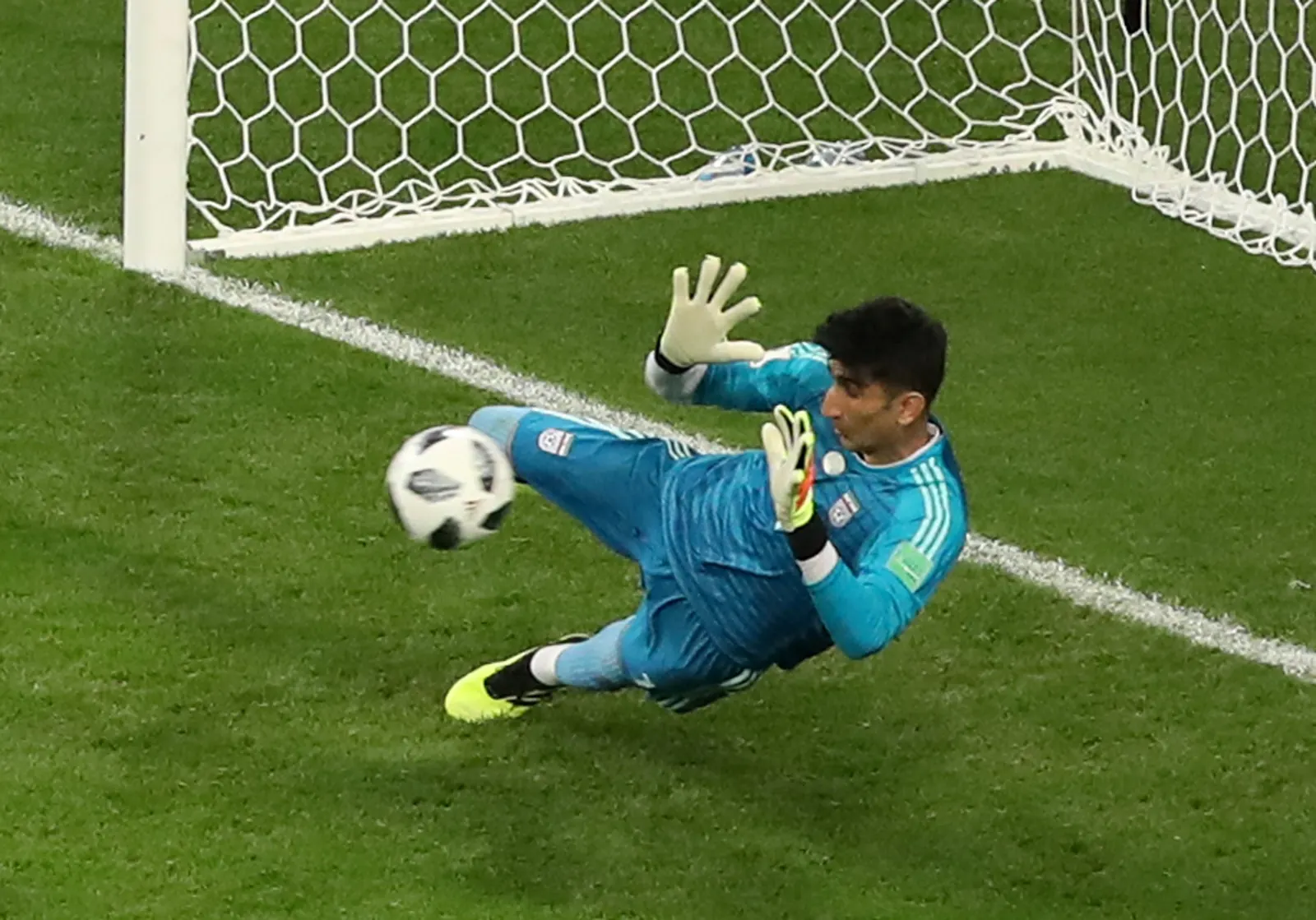 Goleiro Alireza Beiranvand em pose de defesa durante uma partida de futebol.
