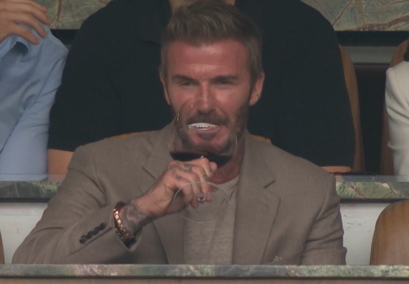 David Beckham, ex-jogador de futebol, sorrindo em um evento esportivo.