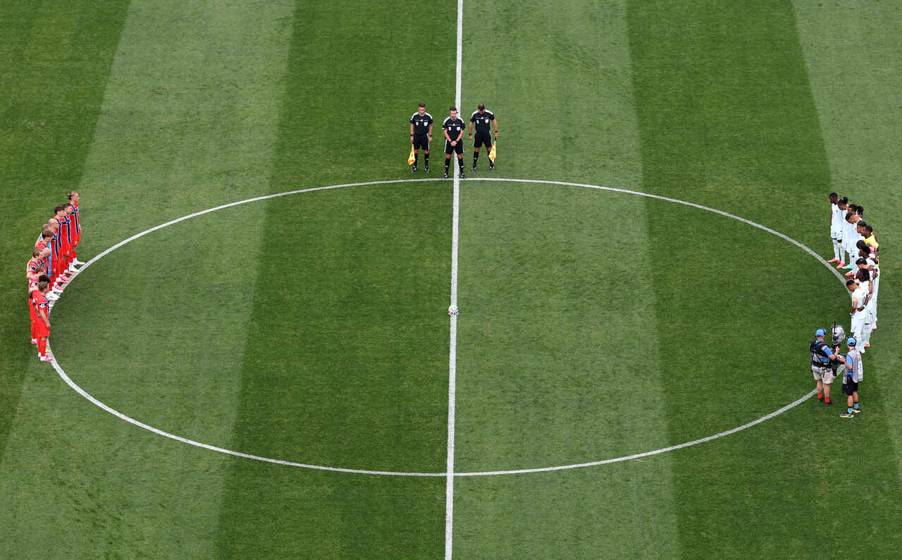 Jogadores e torcedores em um momento de silêncio em campo durante uma partida da Copa do Mundo 2026.