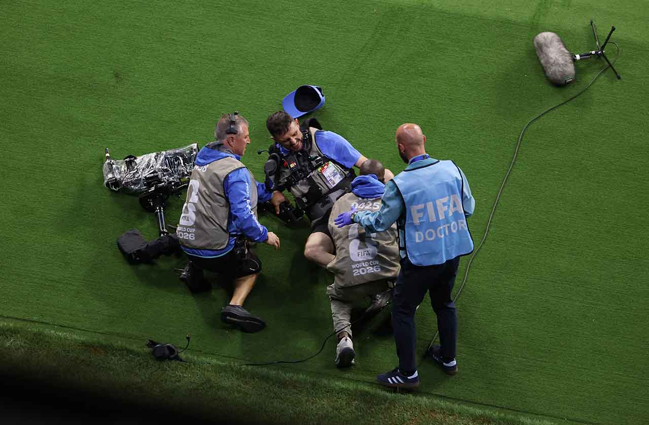 Cinegrafista sendo atendido após colidir com zagueiro do Uzbequistão em partida de futebol