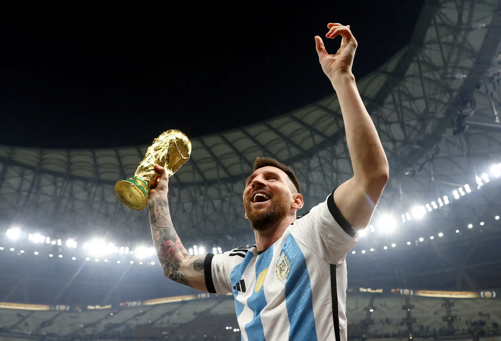 Lionel Messi comemora segurando a taça da Copa do Mundo da FIFA, com a camisa da seleção argentina.