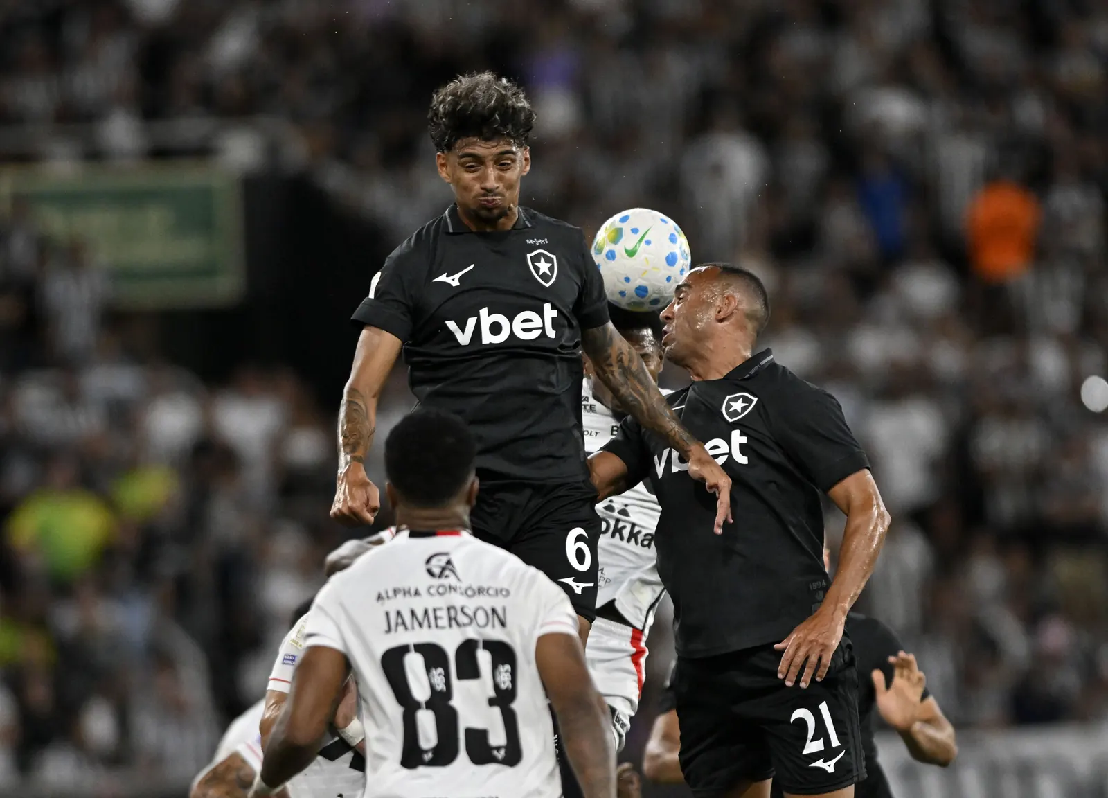 Jogadores estrangeiros do Botafogo reunidos no gramado durante treino, com sorrisos e gestos de camaradagem