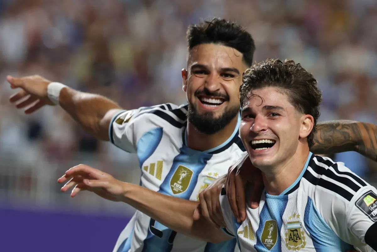 Jogadores de futebol comemorando um gol em um campo de futebol.