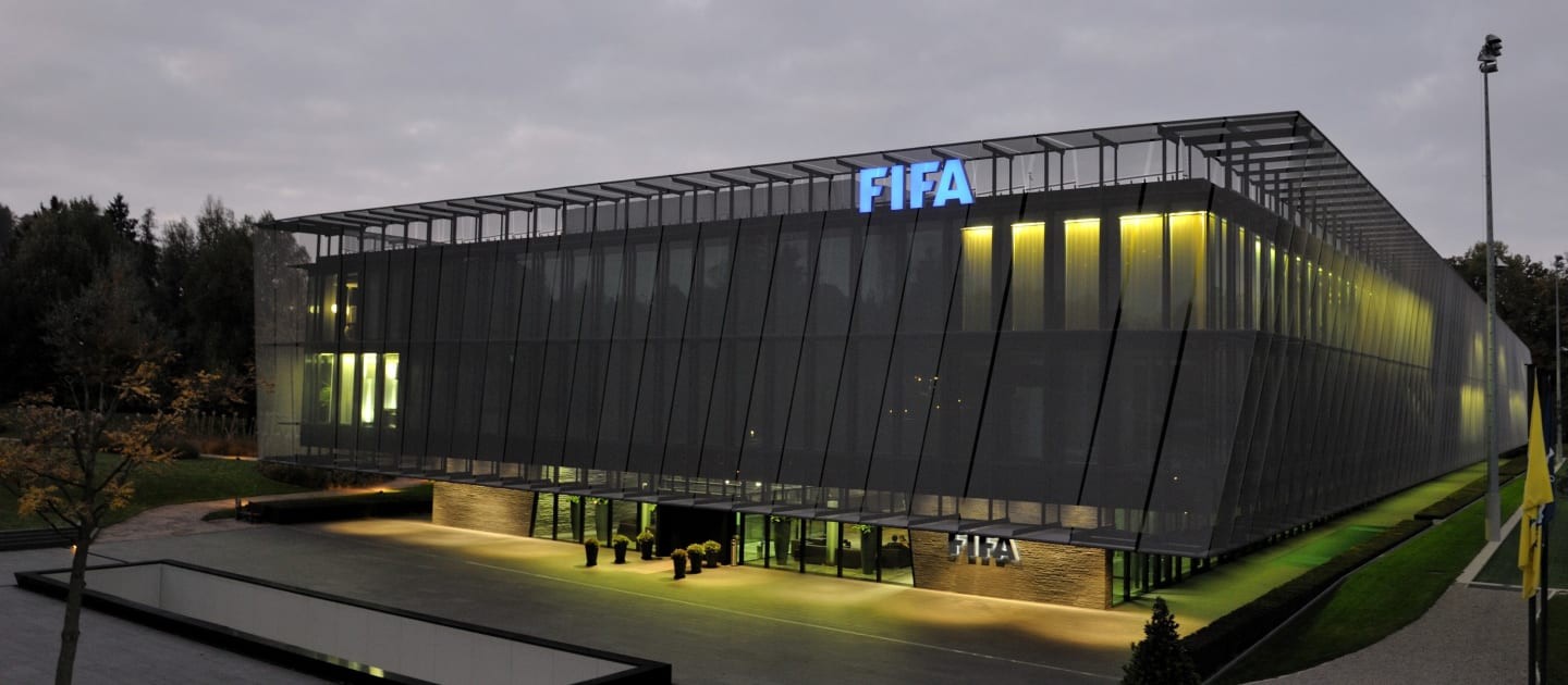 Fachada moderna da sede da FIFA em Zurique, com o logo da organização em destaque.